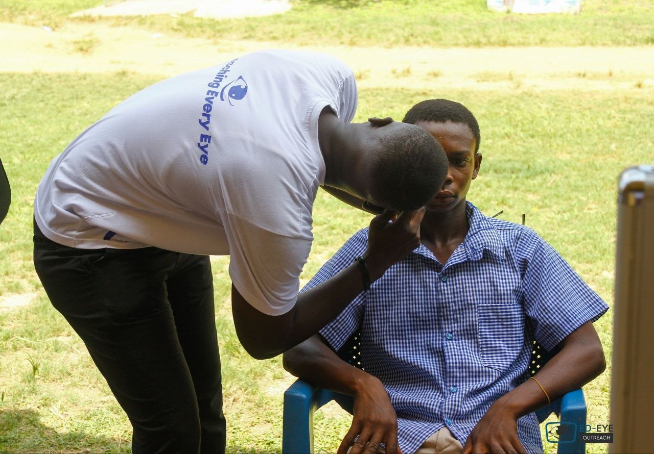 Volunteer conducting an eye examination at an outdoor screening