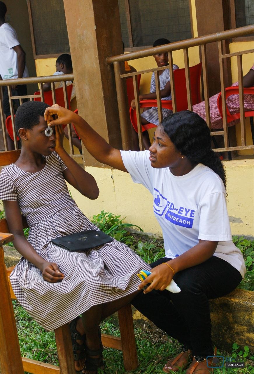 ED-EYE volunteer examining a student using a handheld optical instrument