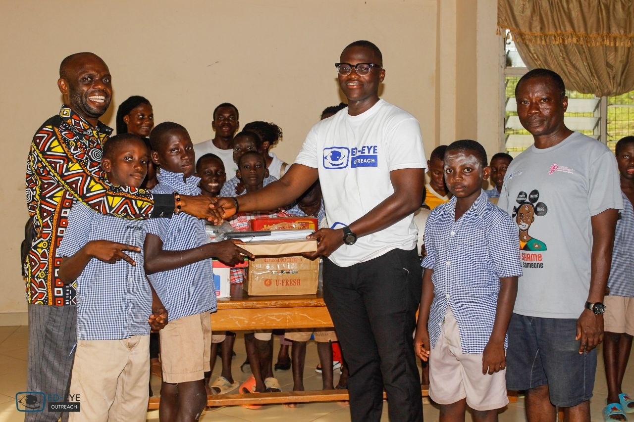 Outreach volunteer presenting donated materials to school representatives